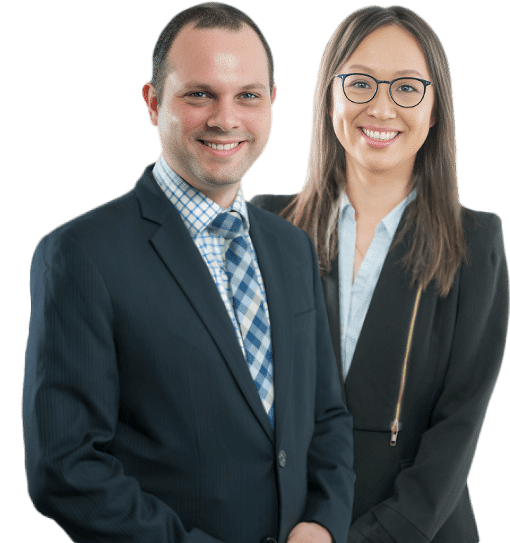 A man and a woman in formal attire stand side by side, smiling like seasoned professionals. The man sports a dark suit with a blue and white checkered tie, while the woman dons a similar suit with a white blouse and glasses, exuding the confidence of no win no fee solicitors.